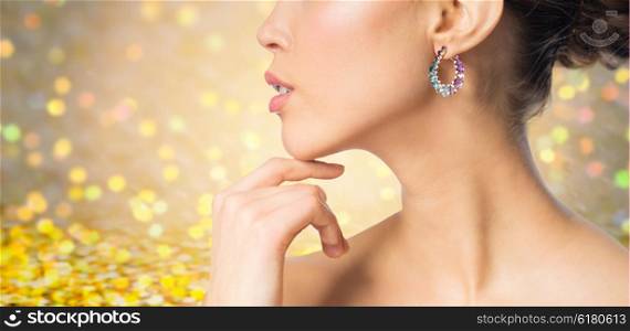 glamour, beauty, jewelry and luxury concept - close up of beautiful woman face with earring over golden holidays lights background