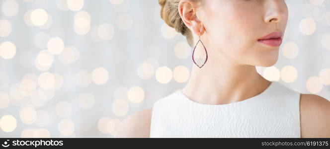 glamour, beauty, jewelry and luxury concept - close up of beautiful woman face with pearl earring over holidays lights background