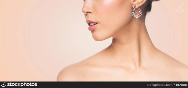 glamour, beauty, jewelry and luxury concept - close up of beautiful woman face with earring over beige background