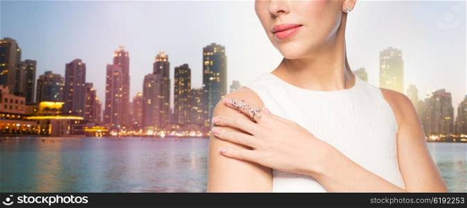 glamour, beauty, jewelry and luxury concept - close up of beautiful woman with golden ring and diamond earring over singapore city skyscrapers background