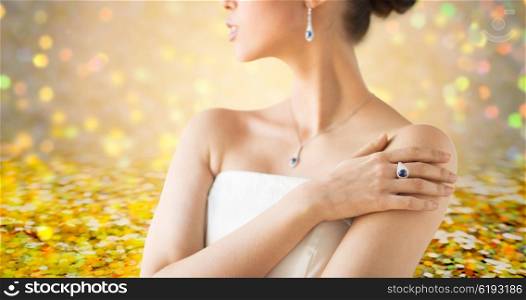 glamour, beauty, jewelry and luxury concept - close up of beautiful woman with finger ring over golden holidays lights background