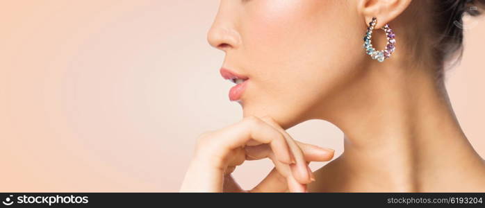 glamour, beauty, jewelry and luxury concept - close up of beautiful woman face with earring over beige background