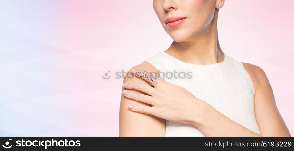 glamour, beauty, jewelry and luxury concept - close up of beautiful woman with golden ring and diamond earring over rose quartz and serenity gradient background