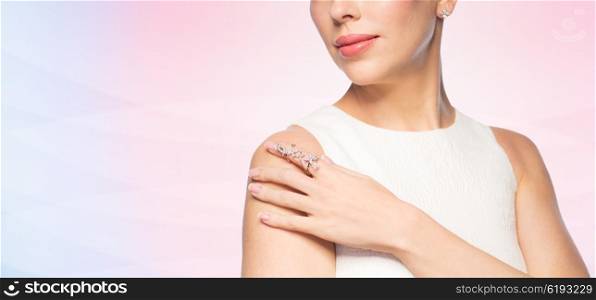 glamour, beauty, jewelry and luxury concept - close up of beautiful woman with golden ring and diamond earring over rose quartz and serenity gradient background