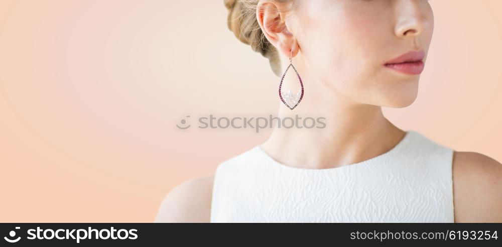 glamour, beauty, jewelry and luxury concept - close up of beautiful woman face with pearl earring over beige background