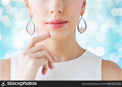 glamour, beauty, jewelry and luxury concept - close up of beautiful woman face with pearl earrings over blue holidays lights background