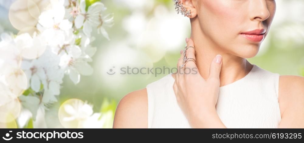 glamour, beauty, jewelry and luxury concept - close up of beautiful woman with golden ring and diamond earring over natural spring cherry blossom