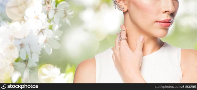glamour, beauty, jewelry and luxury concept - close up of beautiful woman with golden ring and diamond earring over natural spring cherry blossom