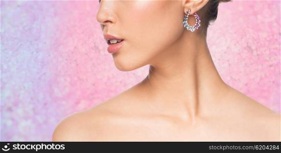 glamour, beauty, jewelry and luxury concept - close up of beautiful woman face with earring over pink glitter background
