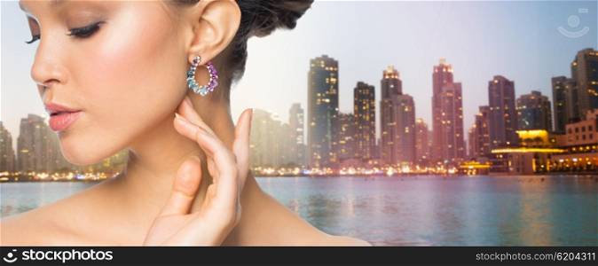glamour, beauty, jewelry and luxury concept - close up of beautiful woman face with earring over singapore city skyscrapers background