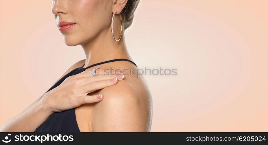 glamour, beauty, jewelry and luxury concept - close up of beautiful woman with golden ring and earring over beige background