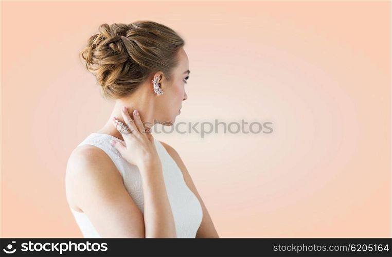 glamour, beauty, jewelry and luxury concept - close up of beautiful woman with golden ring and diamond earring over beige background