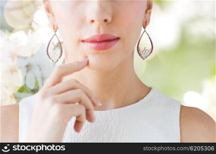 glamour, beauty, jewelry and luxury concept - close up of beautiful woman face with pearl earrings over natural spring cherry blossom