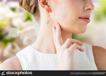 glamour, beauty, jewelry and luxury concept - close up of beautiful woman face with gold and diamond earring over natural spring lilac blossom background