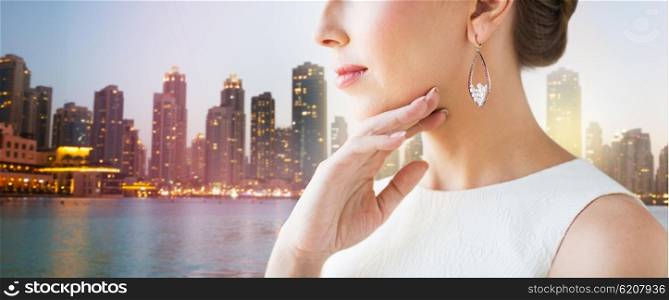 glamour, beauty, jewelry and luxury concept - close up of beautiful woman face with pearl earrings over singapore city skyscrapers background