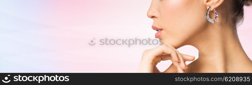 glamour, beauty, jewelry and luxury concept - close up of beautiful woman face with earring over pink background