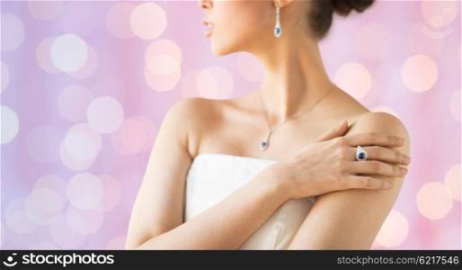 glamour, beauty, jewelry and luxury concept - close up of beautiful woman with finger ring over pink holidays lights background