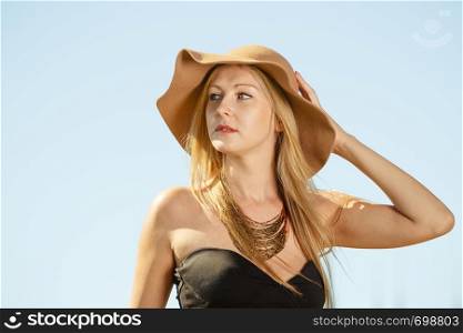 Glamour fashion concept. Portrait of fashionable woman wearing big sun hat and trendy outfit, outdoor shot on sunny day. Portrait of fashionable woman wearing big sun hat