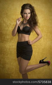 glamour fashion portrait of curly young female with sexy black bra and skirt, stylish necklace and cute make-up. In dynamic pose looking in camera