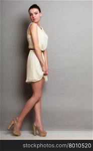 Glamour girl in white dress on gray. Fashion young slim woman posing in full length. Studio photo