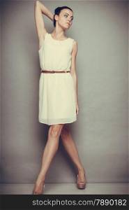 Glamour girl white dress on gray. Fashion young slim woman posing in full length. Studio photo, filtered tone