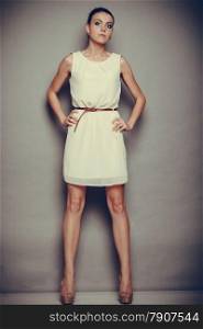 Glamour girl white dress on gray. Fashion young slim woman posing in full length. Studio photo, filtered tone