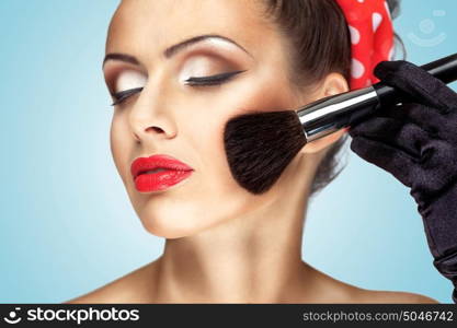 Glamour girl with fashion makeup painting her cheek with brush.