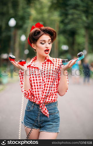 Glamour pin up girl with retro rotary telephones, vintage american fashion. Attractive woman in pinup style. Glamour pin up girl with retro rotary telephones