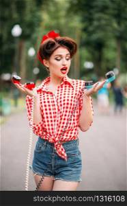 Glamour pin up girl with retro rotary telephones, vintage american fashion. Attractive woman in pinup style. Glamour pin up girl with retro rotary telephones