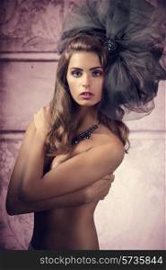 glamour shoot of very pretty woman with naked breast and bizarre, big tulle accessory in the head. Fashion creative style