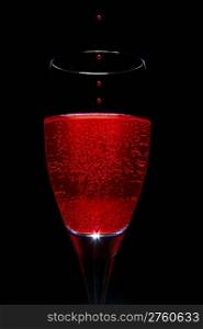 Glas of wine and drups over a black background