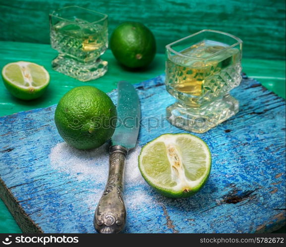 glass alcoholic drink and lime fruits on wooden texture.