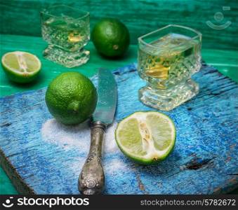glass alcoholic drink and lime fruits on wooden texture.