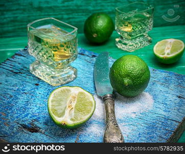 glass alcoholic drink and lime fruits on wooden texture.