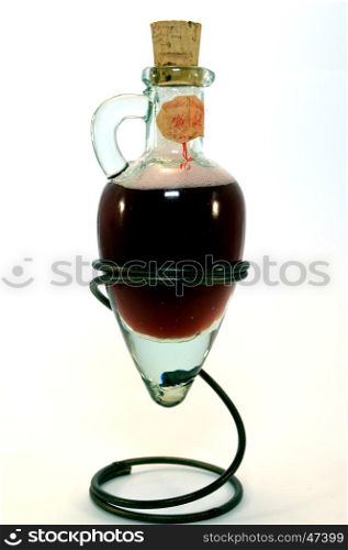 Glass amphora with some red vinegar rest on a tripod in the shape of spring.