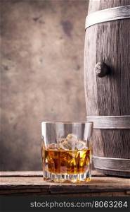 Glass and a barrel of whiskey on wooden table. Glass and a barrel of whiskey