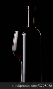 Glass and bottle of red wine on black background