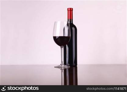 Glass and bottle of red wine over a white background