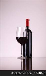 Glass and bottle of red wine over a white background