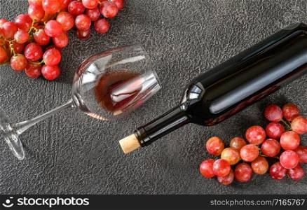 Glass and bottle of red wine with bunch of grapes: top view