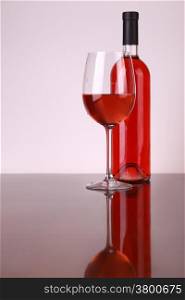 Glass and bottle of rose wine over a white background