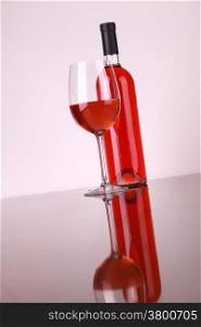 Glass and bottle of rose wine over a white background