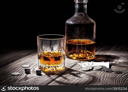 Glass and bottle of whiskey and playing cards and money on wooden table. Glass and bottle of whiskey and playing cards and money