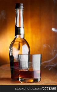 glass and bottle of whiskey with smoke