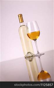 Glass and bottle of white wine over a white background