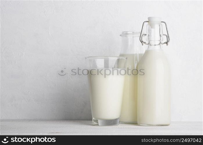 Glass and bottles of milk on white wooden table background with copy space still life
