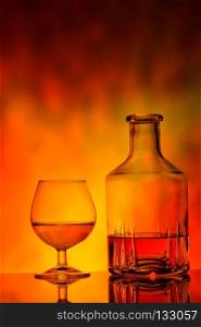 Glass and decanter of cognac on fire background. Glass and decanter of cognac