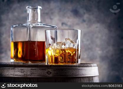 Glass and decanter of whiskey on old wooden barrel