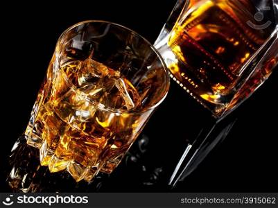 Glass and decanter of whiskey shot at an angle on black glass