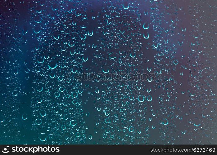 Glass background with water drops on it, view from the home window on the rainy night, autumn depression concept